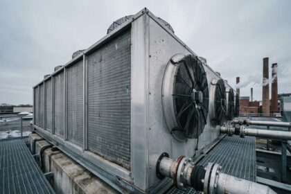 Dry cooler industriel monté en toiture d'une usine de fabrication avec échangeurs thermiques en aluminium et ventilateurs axiaux visibles